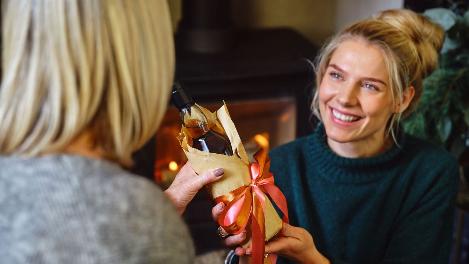 Frau übergibt ein Getränke-Geburtstagsgeschenk an seine Schwester oder Freundin.